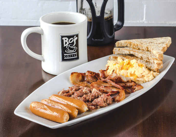 Pequeno-almoço com ovos, torradas, salsichas e bacon, servido num prato