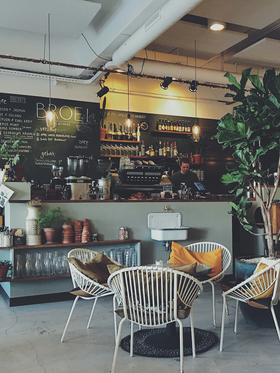 Interior do café Celluz com mesas, plantas e balcão