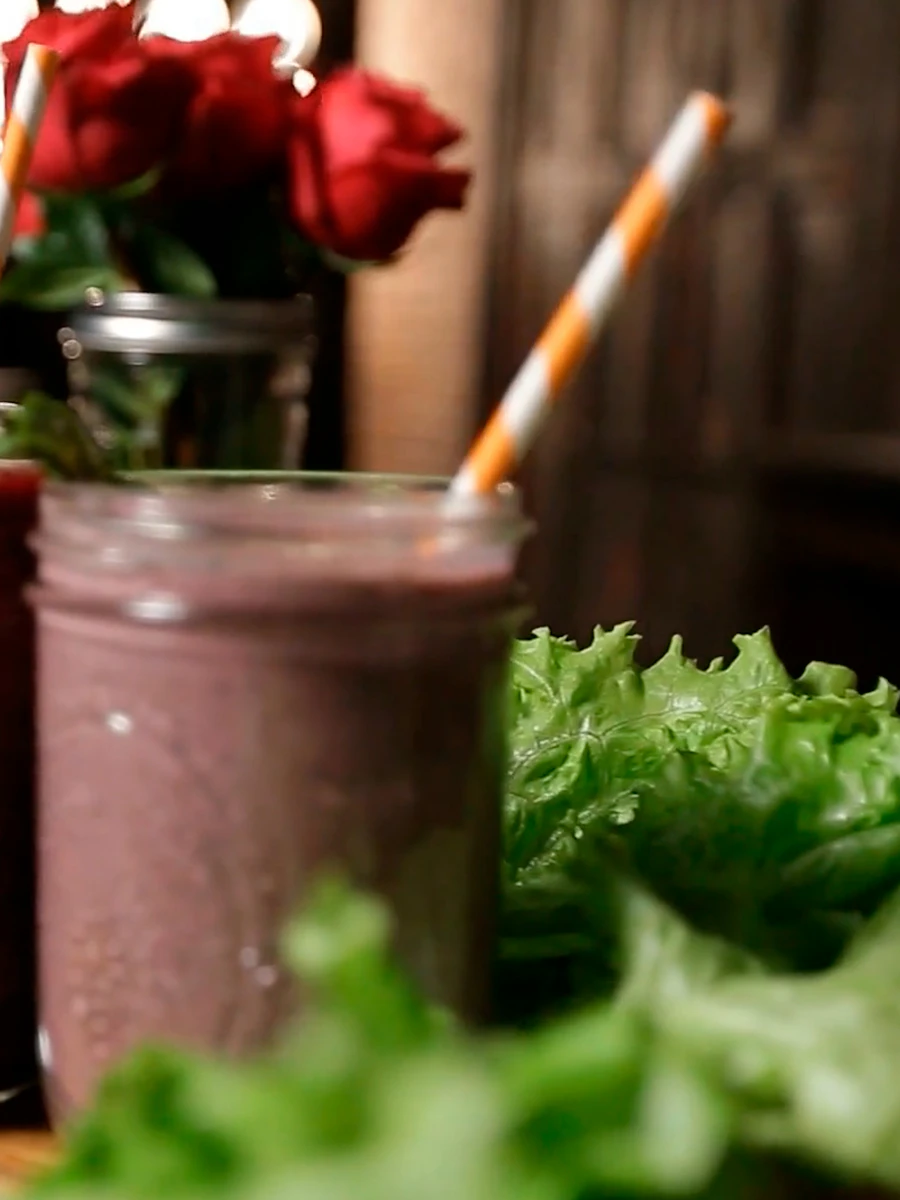 Batido natural de fruta num copo com palha, sobre uma mesa