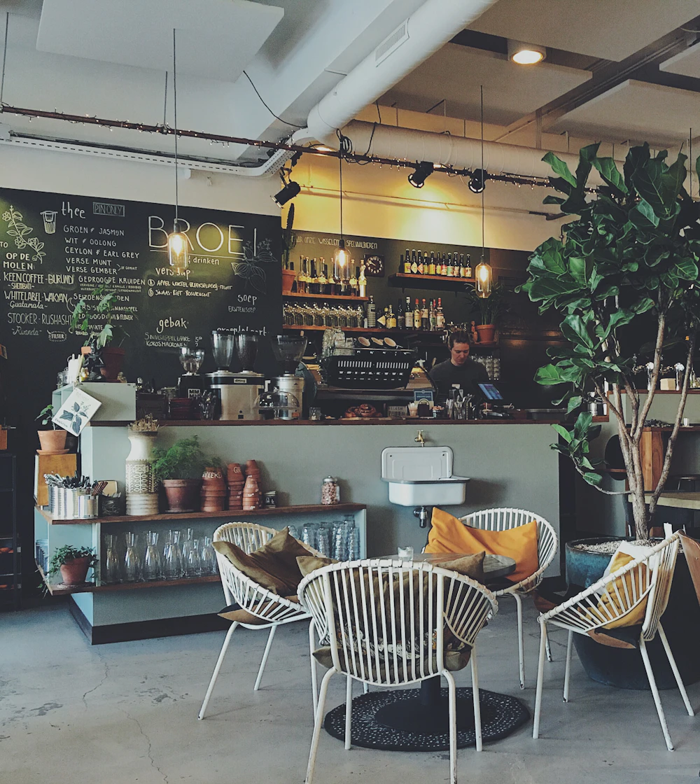 Interior acolhedor do café Celluz, com mesas, plantas e balcão
